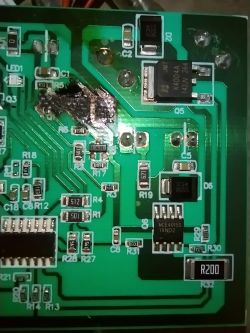 Płytka drukowana z uszkodzeniem spowodowanym przegrzaniem, widoczne komponenty elektroniczne.