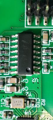Close-up of a green printed circuit board with a chip and electronic components.
