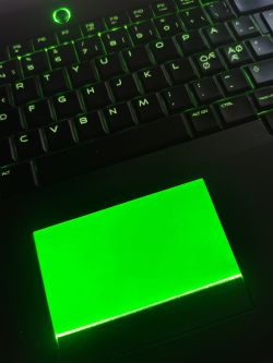 Podświetlona klawiatura i touchpad w laptopie z zielonym światłem.