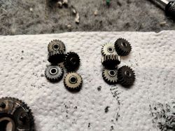 Małe metalowe zębatki mechaniczne leżące na białym ręczniku papierowym, przygotowane do wymiany w przekładni.