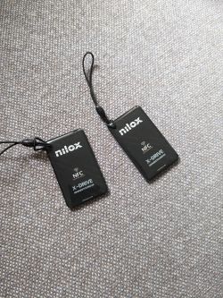 Dwie czarne karty NFC Nilox leżące na szarej tkaninie.