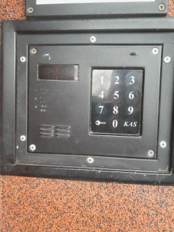Intercom Panel with Keypad and Display Close-up of an intercom panel with a keypad and a display on a wall background.