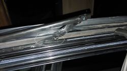 Zbliżenie na uszkodzoną prowadnicę szyby w oknie.