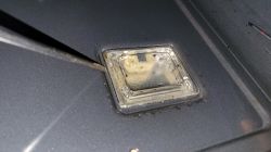 Śrubokręt podważający szklane szkiełko lampy w piekarniku, widok z bliska.