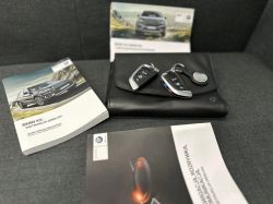 BMW car keys on a black leather folder next to user manuals.