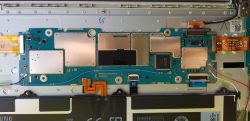 Wnętrze urządzenia elektronicznego z widoczną płytą główną pokrytą elementami zalutowanymi.