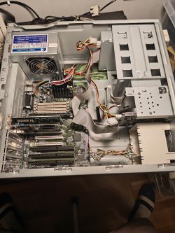 Wnętrze starej obudowy PC z zasilaczem Enlight, płytą główną i taśmami IDE