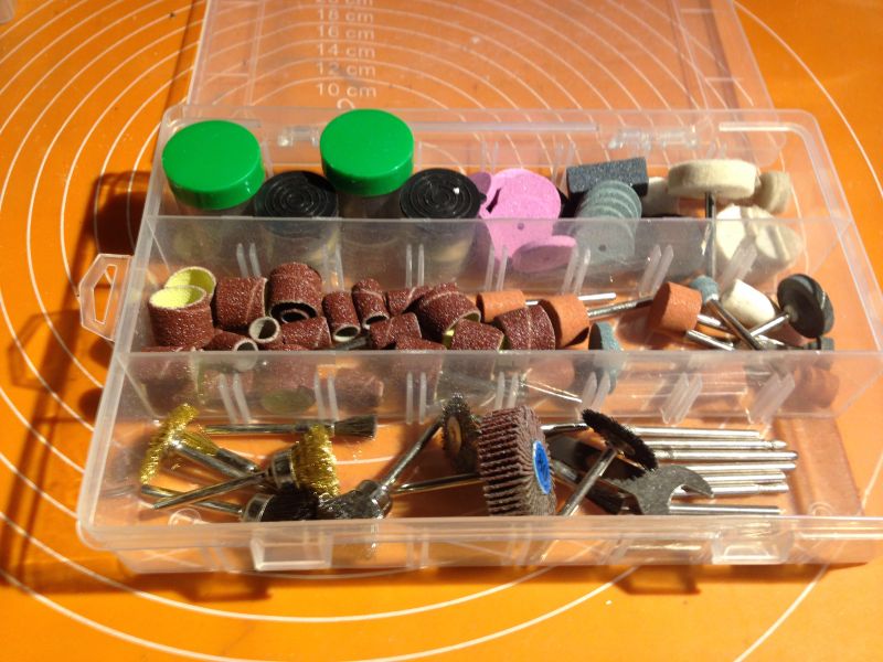 Zestaw akcesoriów do szlifierki w przegródce plastikowego pudełka.