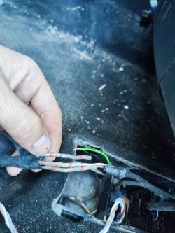 Repairing car seat wires with a visible damaged green wire.