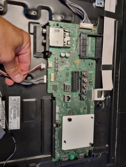 Płyta główna telewizora Sony z odłączonymi przewodami, widoczne elementy elektroniczne.