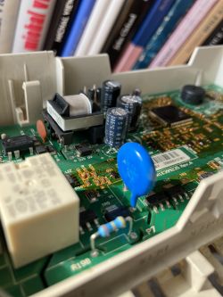 Dishwasher control board with visible electronic components, capacitors, and a resistor.