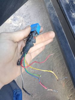 Przewody elektryczne z nadpaleniami i niebieskim przekaźnikiem w dłoni