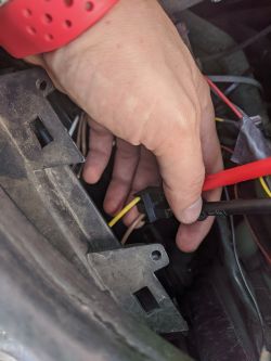 Ręka trzymająca przewody i gniazdo elektryczne w samochodzie.