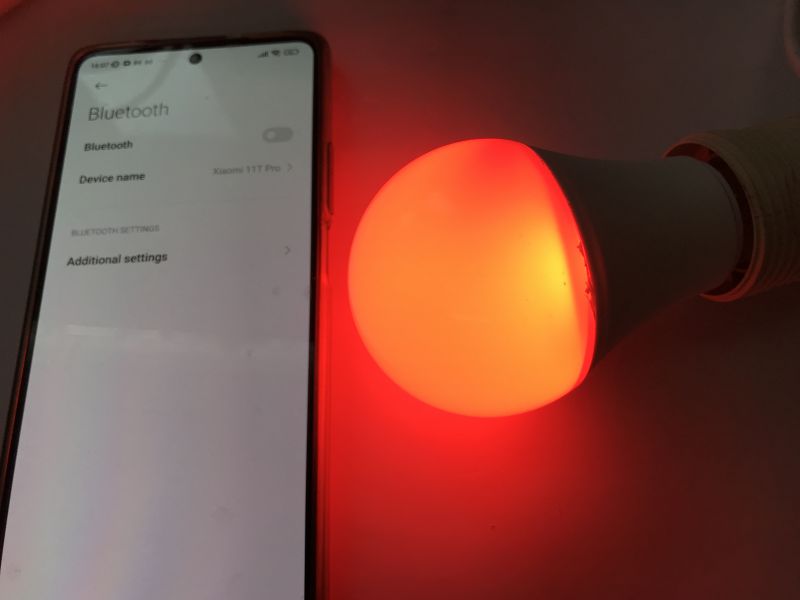 Pairing RGB Bluetooth Bulb with Smartphone App Smartphone with open Bluetooth settings next to a red-glowing RGB bulb.