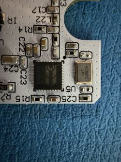 Close-up of a PCB with a black IC and a metal can labeled 26.000C73H.