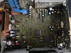 Widok wnętrza urządzenia elektronicznego z płytką drukowaną i elementami takimi jak kondensatory i układy scalone.