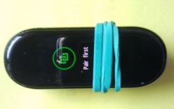 Opaska Mi Band z gumką, na ekranie ikona parowania i napis „Pair first”.