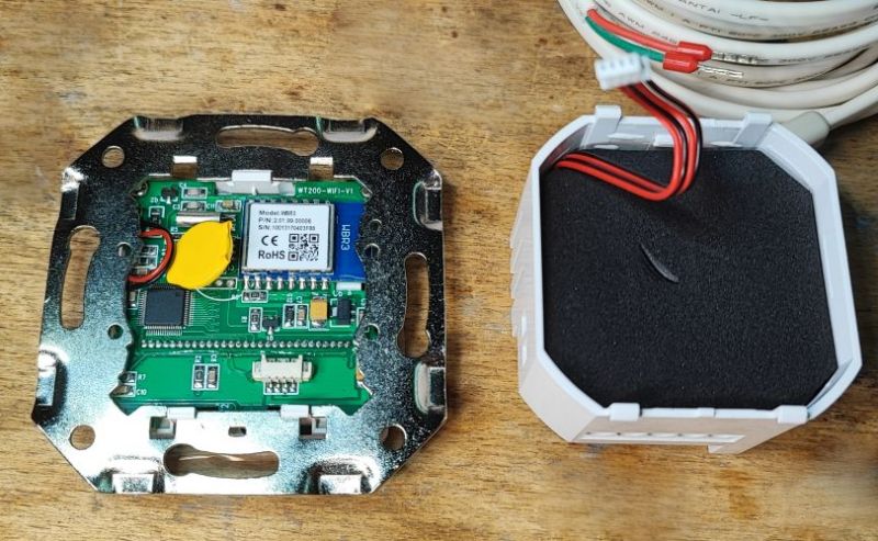 Thermostat PCB in a metal mounting frame with WBR3 WiFi module and sensor cable on a wooden surface