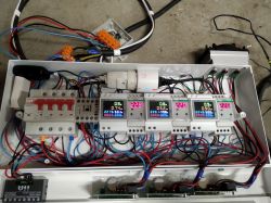 Panel elektryczny z miernikami napięcia i natężenia, w którym widać liczne przewody oraz wyłączniki nadprądowe.