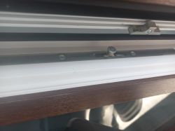 Zbliżenie na mechanizm okna z metalowym zaczepem i trzpieniem ryglującym