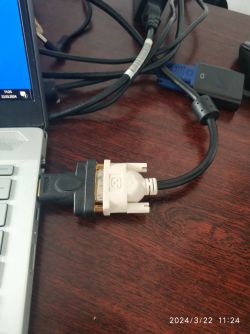 Widoczne połączenie HDMI z adapterem DVI podłączonym do laptopa na biurku.