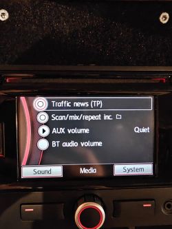 Car radio RNS315 display showing sound settings menu with options: traffic news, scan/mix/repeat, AUX volume, and BT audio volume.