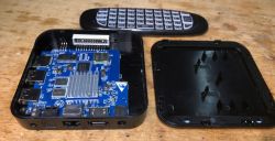 Wnętrze odłączonego Smart TV Android Box z widocznym układem elektronicznym i pilotem.