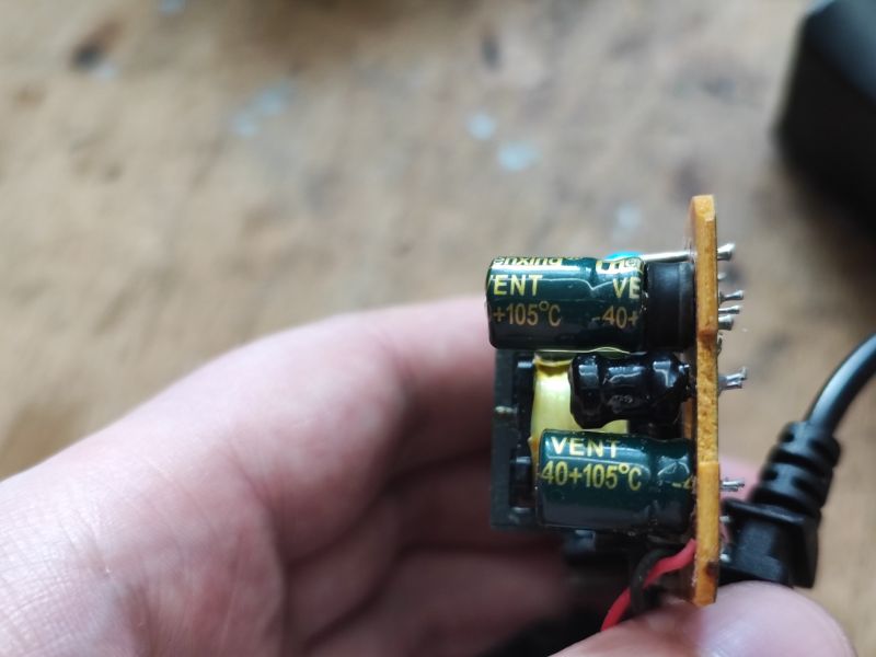 Zbliżenie na uszkodzony kondensator w zasilaczu.