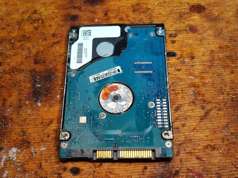 Back Side of Seagate Momentus 5400.6 Hard Drive Photo of the back side of a Seagate Momentus hard drive showing the circuit board on a wooden surface.
