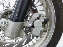 Zbliżenie na zacisk hamulcowy Brembo i czujnik prędkości przy przednim kole motocykla