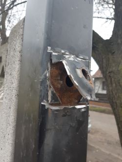 Zniszczony metalowy element konstrukcyjny z otworami i śladami korozji.