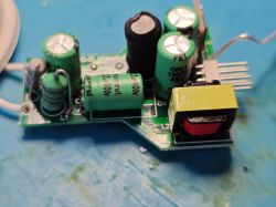 Close-up of a PCB with green capacitors, a resistor, and a yellow transformer.