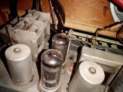 Wnętrze starego gramofonu z widocznymi lampami elektronowymi i elementami elektronicznymi.