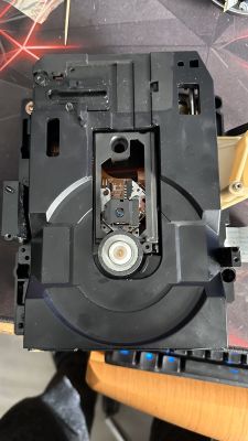 Widok zbliżony na mechanizm CD Technics SL-PS700 z widocznym laserem i kołem zębatym.