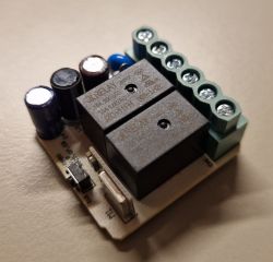 Close-up of a PCB with two relays, electrolytic capacitors, and a green screw terminal block
