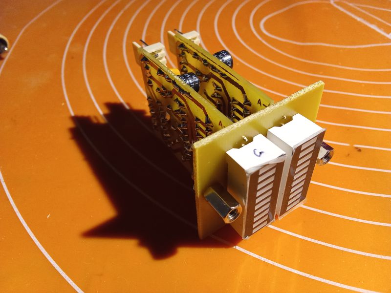 Electronic circuit board with protruding components on an orange surface.