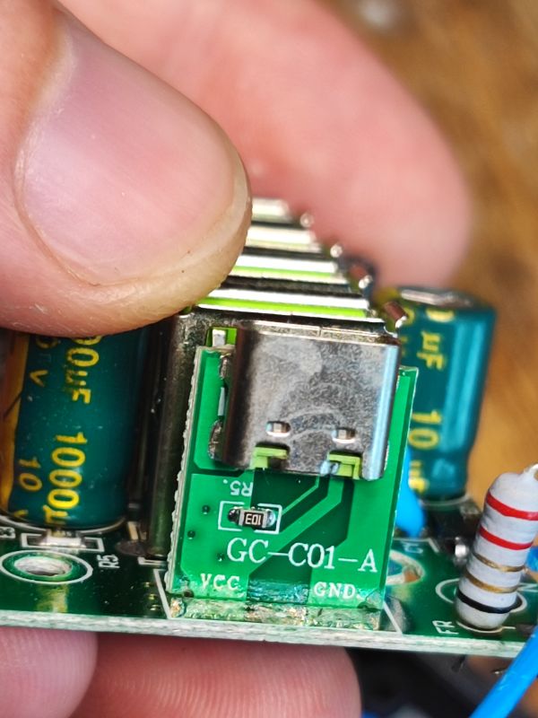 Zbliżenie na port USB-C na płytce drukowanej w zasilaczu, widoczne szczegóły lutowania i elementy elektroniczne.