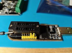 Close-up of CH341A programmer with connected pins on a blue mat.