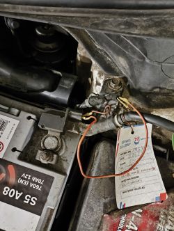 Zdjęcie akumulatora samochodowego z widocznymi przewodami, z których jeden wygląda na odłączony lub źle podłączony.