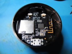 Open electronic device case with exposed PCB Inside of a round electronic device showing a PCB with a micro USB port and a microSD card slot.