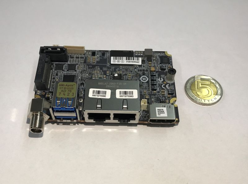 Płytka elektroniki z gniazdami RJ45, USB i złączem koncentrycznym; obok moneta 5 zł