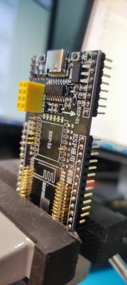 ESP-12F board clamped in a vice with visible pins and components.