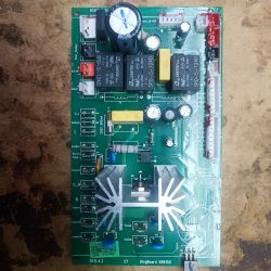 Płyta drukowana z różnymi elementami elektronicznymi, w tym kondensatorami i przekaźnikami.