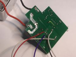 A PCB with attached wires, visible traces, and soldered connections on a green circuit board.