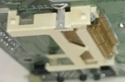 Close-up of a white connector with a brown FFC/FPC ribbon cable on a green PCB