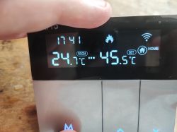 Electronic thermostat display showing room temperature and set temperature.