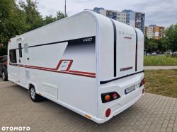 Bailey camper trailer in front of apartment buildings.