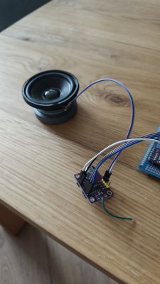 Small speaker and amplifier board with connected wires on a wooden tabletop