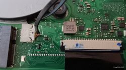 Zbliżenie na wewnętrzny obwód drukowany laptopa z widocznymi elementami elektrycznymi, w tym złączami i układami scalonymi.