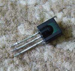 Three-pin IR receiver on a textured surface.